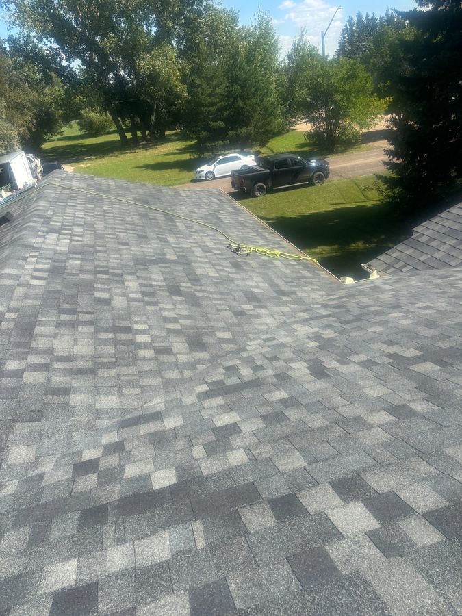 Completed grey shingle roof with summer greenery near Wroxton Saskatchewan