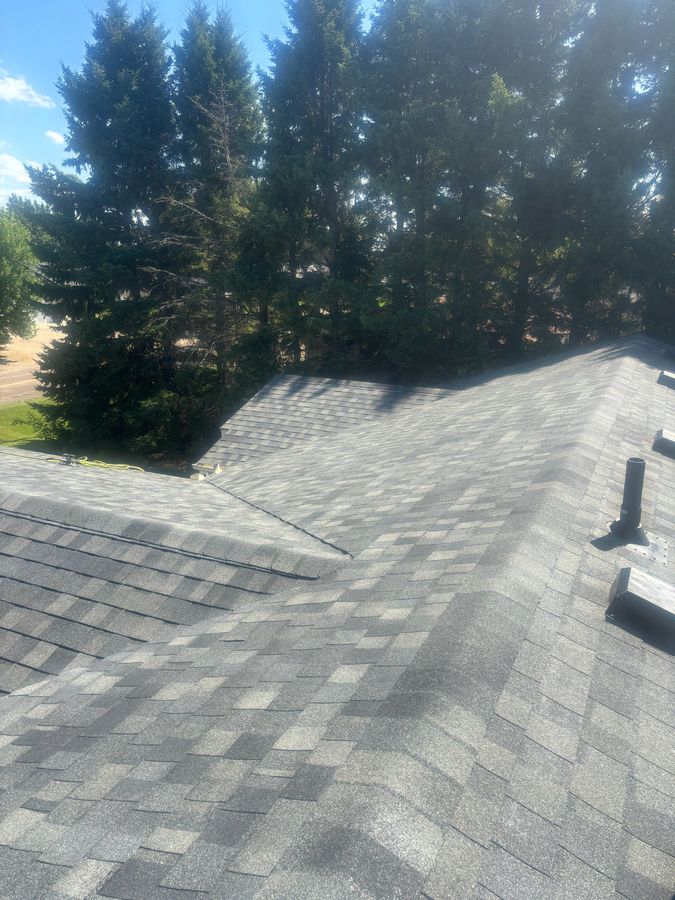 Completed pewter grey shingle roof surrounded by evergreen trees near Springside Saskatchewan