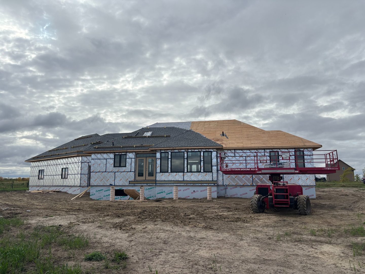 Large new construction home with boom lift during roof installation near Churchbridge Saskatchewan
