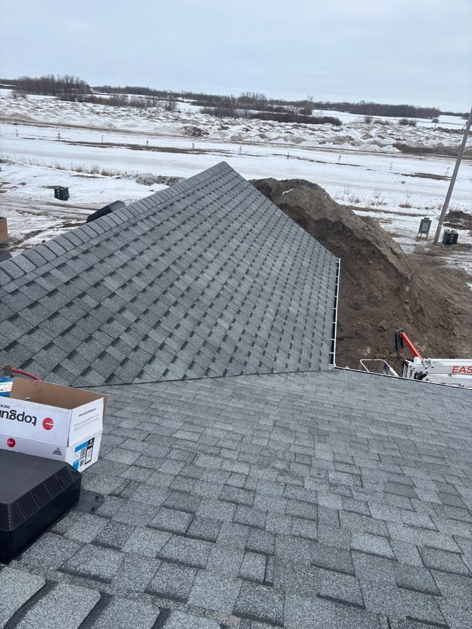 Winter roof installation with box vents overlooking snowy Saskatchewan prairie near Rhein